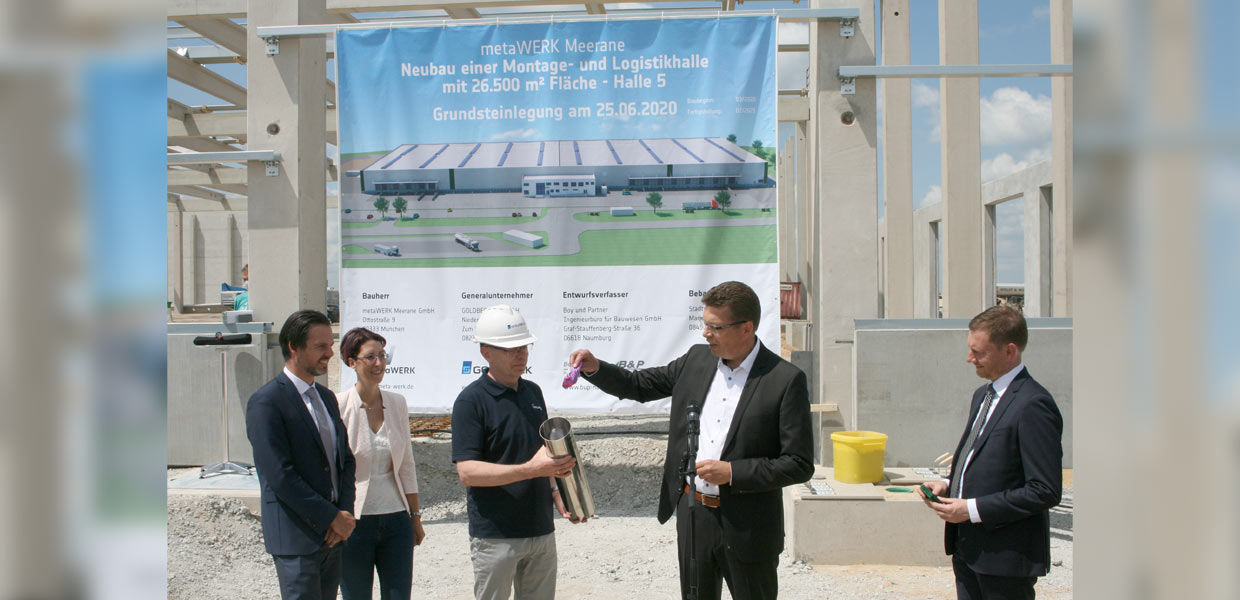 Grundsteinlegung für das externe Versorgungszentrum von VW Sachsen im Industriepark Meerane. In die zukünftig fest mit dem Gebäude verbundene Metallhülse packte der Geschäftsführer von VW Sachsen, Reinhard de Vries, einen Mund-Nasen-Schutz im ersten Camouflage-Design des ID.3 als Beleg für die Investition in Corona-Zeiten. Von Ministerpräsident Michael Kretschmer (r.) gab es eine Münze aus Meissener Porzellan. Cathleen Frost, Geschäftsführerin der Metawerk Meerane GmbH, legte einen Masterplan des Gebietes bei und Jörg Bachmann von Goldbeck einen Bauplan nebst Zollstock.