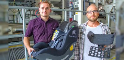 Norbert Schramm (l.) und Tomasz Osiecki zeigen in der Halle des MERGE Technologiezentrums der TU Chemnitz den fertigen Kindersitz mit eingebauter Kopfstütze sowie die dort hergestellte Organoblech-Preform mit Trägerplatte. Die mit Partikelschaum überschäumte Kopfstütze stellt im Fall eines Aufpralls eine gute Crashperformance sicher.